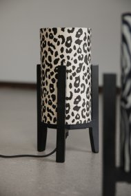 Eruca 34cm Leopard bordslampa från Markslöjd - Lampfoten i svart tr&auml; kombineras med en cylinderformad textilsk&auml;rm i offwhite och brunt leopardm&ouml;nster, vilket ger lampan en trendig och personlig karakt&auml;r.