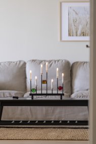 Elljusstake 7ljus Svart från Konstsmide - De sju ljusen ramas in av dekorativa f&auml;rgade glasdetaljer i gr&ouml;nt, r&ouml;tt och b&auml;rnstensgult, vilket skapar en elegant och festlig atmosf&auml;r.