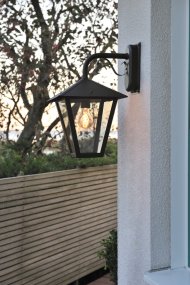 Benu Svart utelampa från Konstsmide - Lampans klassiska lyktform och robusta material g&ouml;r den till ett perfekt val f&ouml;r dig som vill skapa en inbjudande atmosf&auml;r vid entr&eacute;er eller l&auml;ngs g&aring;ngv&auml;gar.