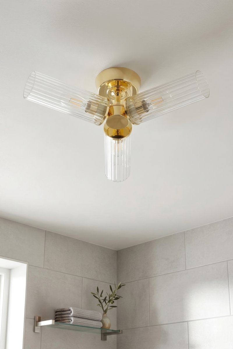 Rimini Ø40 Mässing badrumslampa från Markslöjd - Rimini &auml;r en elegant taklampa som kombinerar en blank m&auml;ssingfinish med tre avl&aring;nga sk&auml;rmar i klart, ribbat glas.
