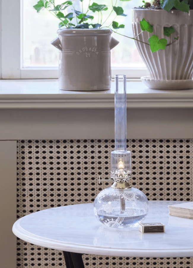 Fotogenlampa Oval Marja Transparent från Strömshaga - En vacker rund fotogenlampa i klarglas med vackra vita handm&aring;lade blommor, br&auml;nnare i m&auml;ssing och br&auml;nnr&ouml;r i klart glas.