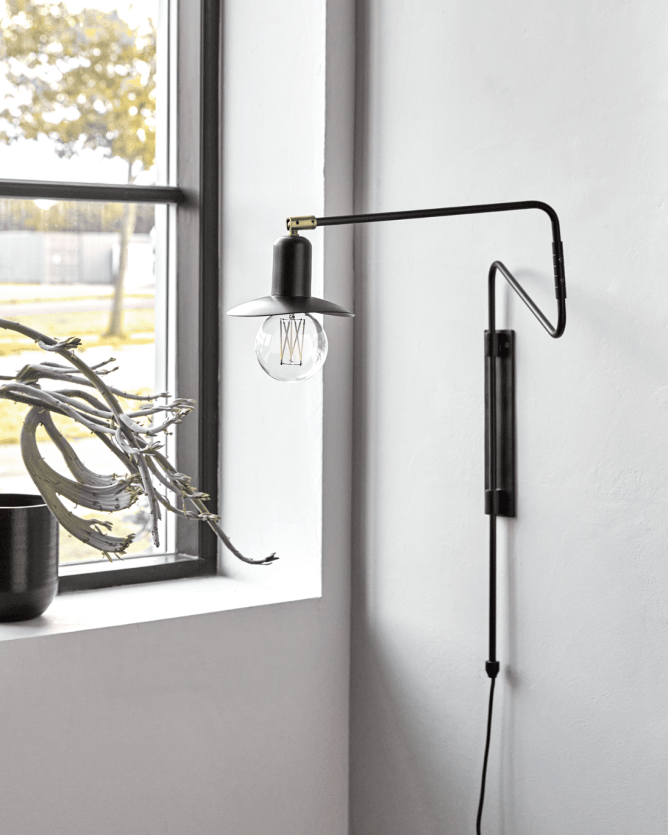 Swing 35cm Svart vägglampa från House Doctor - Den v&auml;lk&auml;nda vridbara designen i en elegant svart finish kompletteras av en charmig liten lampsk&auml;rm som skapar en mysig atmosf&auml;r och ger en k&auml;nsla av sofistikering.