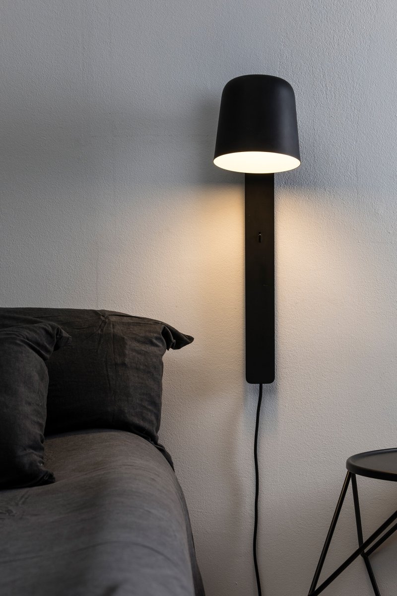 Tila 46cm Svart läslampa från Faro Barcelona - Den svarta st&aring;lstrukturen i nordisk stil rymmer inte bara en fullt justerbar ljusk&auml;lla, utan fungerar &auml;ven som praktisk hylla f&ouml;r en bok eller tidskrift.
