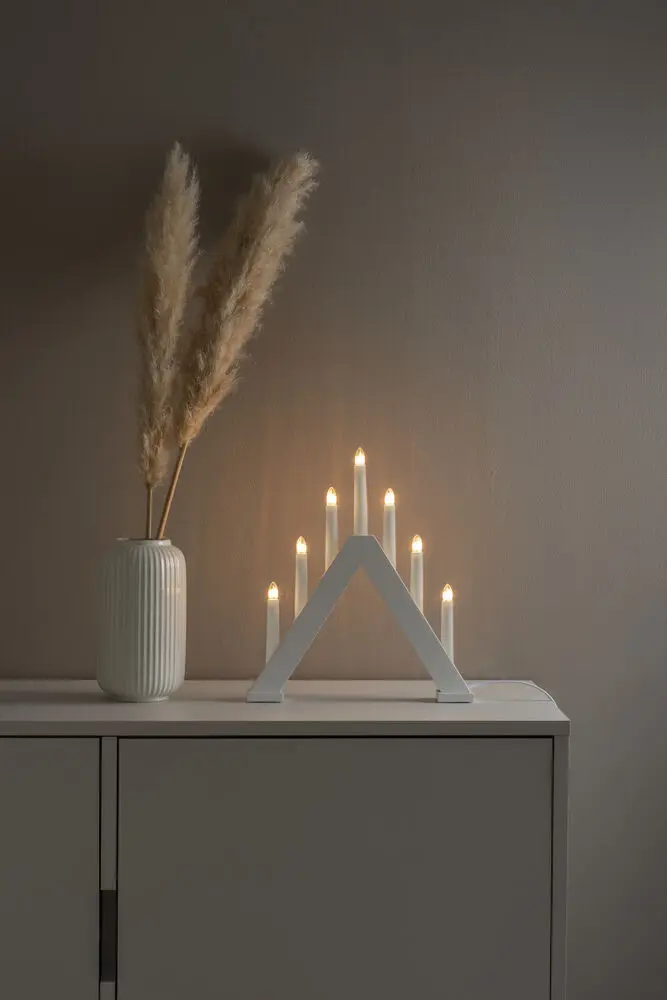 Elljusstake 7ljus Vit från Konstsmide - Den klassiska pyramidformen kombineras med en minimalistisk design, vilket g&ouml;r den till en perfekt inredningsdetalj i b&aring;de traditionella och moderna hem.
