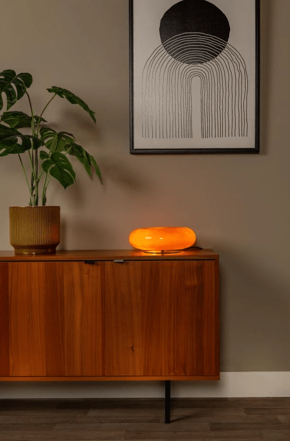 Sentino 10cm Orange bordslampa från Lucide - Denna unika bordslampa kombinerar en glansigt lackerad glaskropp i donutform med en elegant metallbas &ndash; ett stiluttryck som b&aring;de drar blickarna till sig och lyfter rummets helhetsk&auml;nsla.