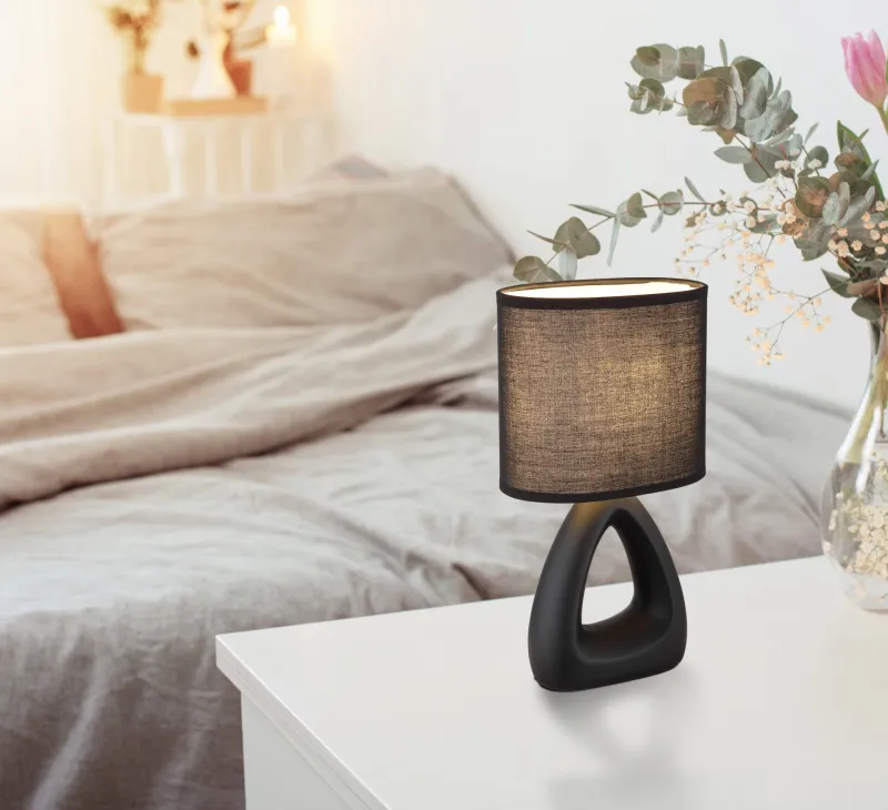 Triangle 30cm Svart bordslampa från Globo Lighting - Den triangelformade basen med ett stilrent utskuret h&aring;l ger ett modernt intryck, medan den ovala textilsk&auml;rmen i svart f&auml;rg sprider ett behagligt och j&auml;mnt ljus.