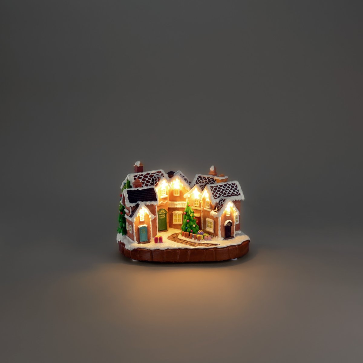 Pepparkaksby 17cm Brun från Konstsmide - De sn&ouml;t&auml;ckta taken, f&auml;rgglada d&ouml;rrarna och den dekorerade granen i mitten ger k&auml;nslan av en sagolik julmilj&ouml;.