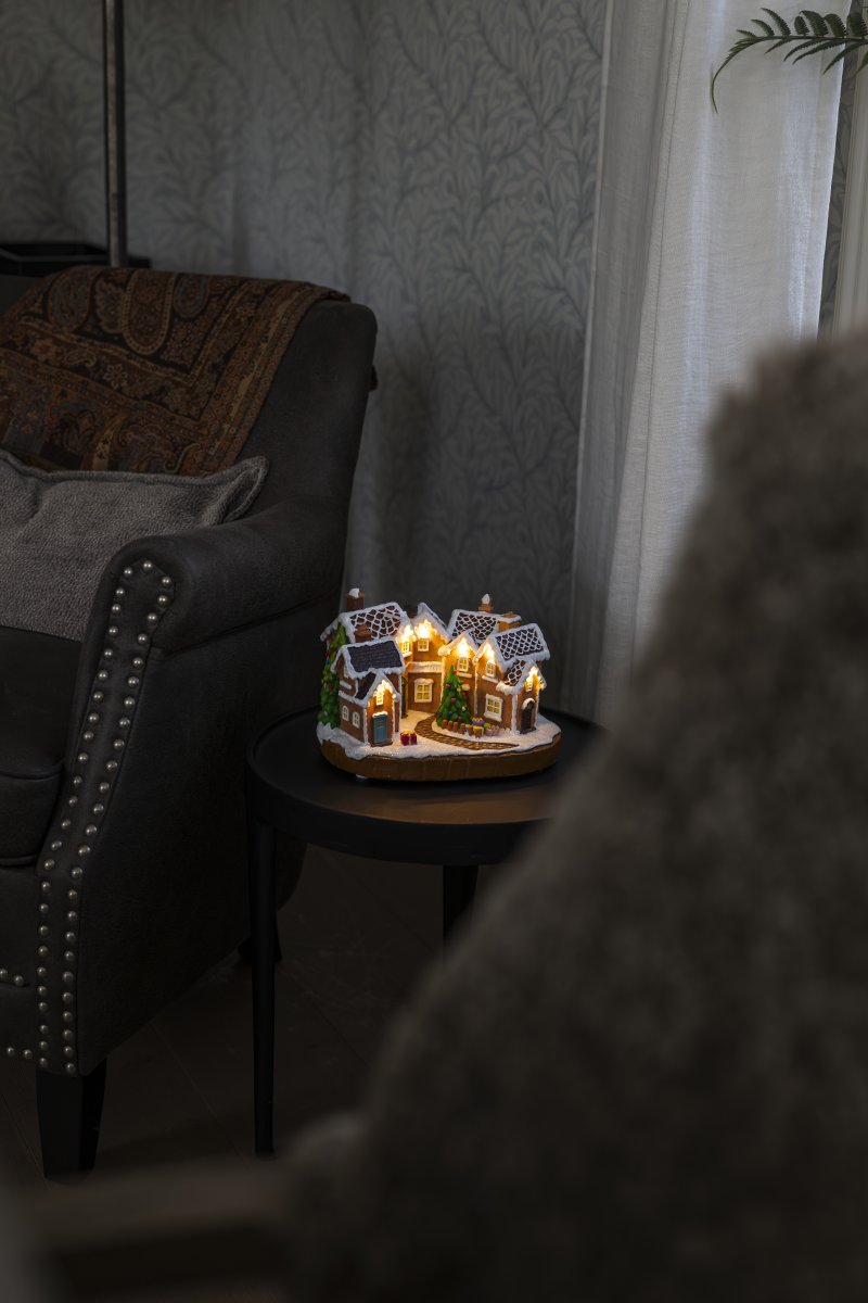 Pepparkaksby 17cm Brun från Konstsmide - De sn&ouml;t&auml;ckta taken, f&auml;rgglada d&ouml;rrarna och den dekorerade granen i mitten ger k&auml;nslan av en sagolik julmilj&ouml;.