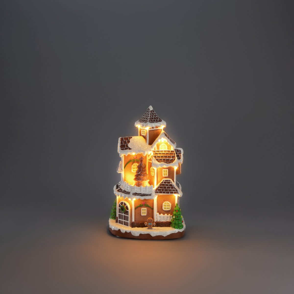 Pepparkaksby 30cm Brun från Konstsmide - Det detaljrika huset med sn&ouml;t&auml;ckta tak, lysande f&ouml;nster och dekorerad gran sprider ett varmt och inbjudande sken i rummet.