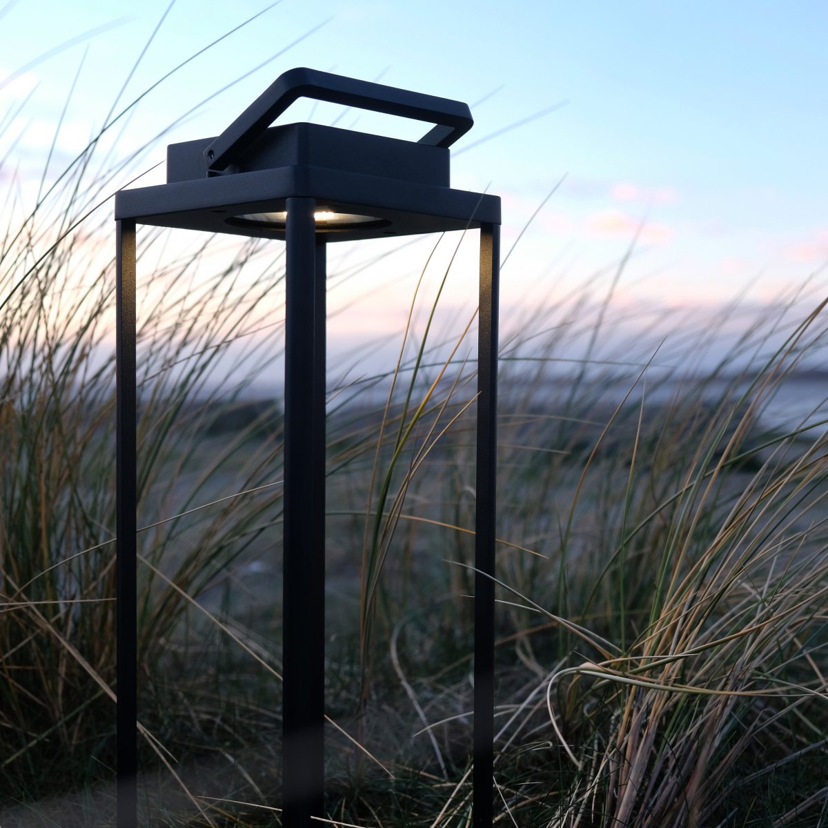 Lucca 34cm Svart portabel från Dyberg Larsen - Lucca-lanternan &auml;r tillverkad i robust metall med b&auml;rhandtag och inbyggd LED i toppen, perfekt som dekoration f&ouml;r terrassen, balkongen eller vid ytterd&ouml;rren.