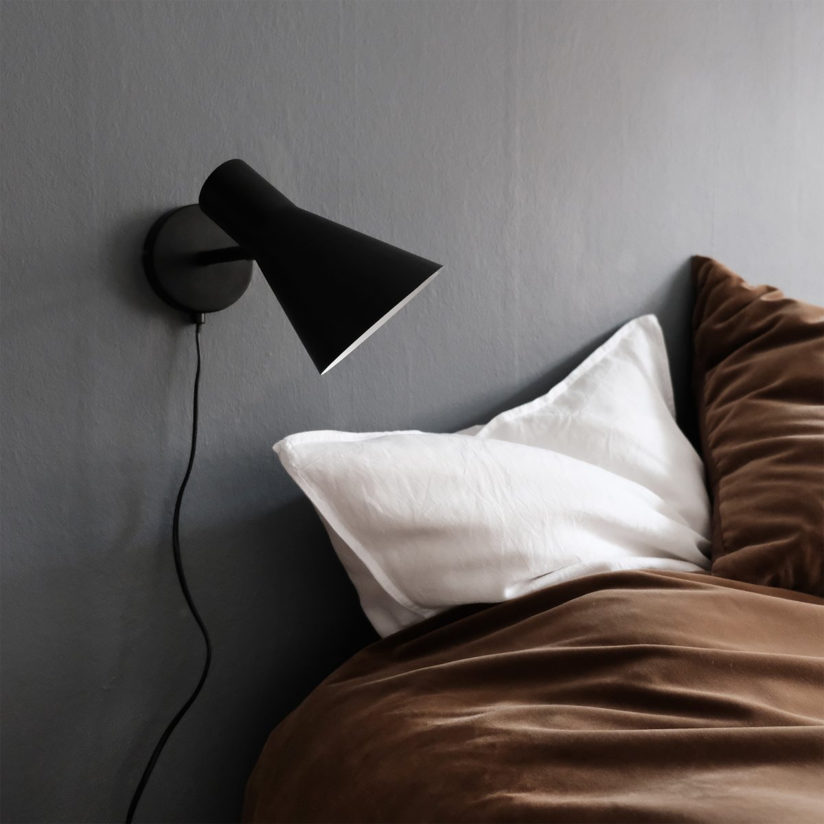 DL12 Svart läslampa från Dyberg Larsen - Med sin moderna, mattsvarta design och vinklade sk&auml;rm ger DL12 ett fokuserat och behagligt ljus, idealiskt f&ouml;r l&auml;sh&ouml;rnor eller som s&auml;nglampa.