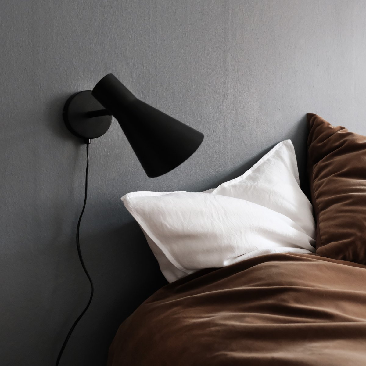 DL12 Svart läslampa från Dyberg Larsen - Med sin moderna, mattsvarta design och vinklade sk&auml;rm ger DL12 ett fokuserat och behagligt ljus, idealiskt f&ouml;r l&auml;sh&ouml;rnor eller som s&auml;nglampa.