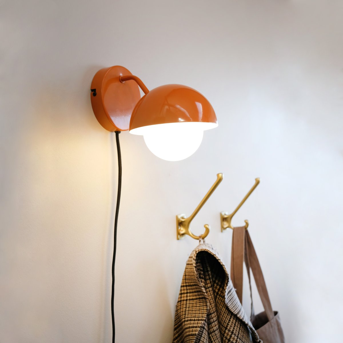 Rose Ø15 shiny orange vägglampa från Dyberg Larsen - Glaskupolen fungerar som en naturlig ljusspridare och skapar en varm och inbjudande atmosf&auml;r i rummet.