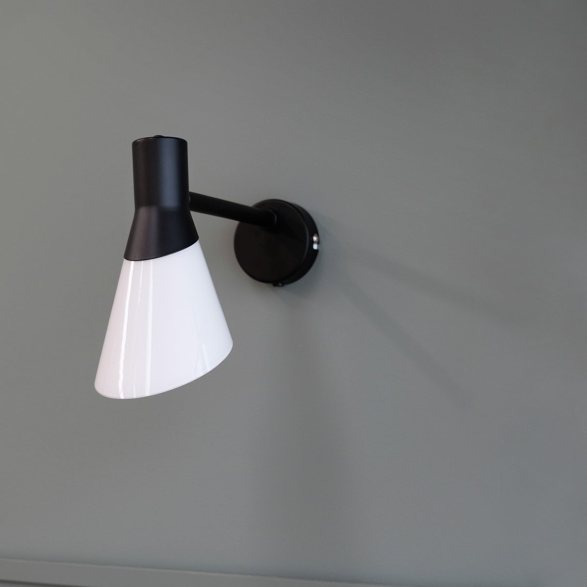 Gent 30cm Svart vägglampa från Dyberg Larsen - Gent &auml;r en modern och stilren v&auml;gglampa med en lampsk&auml;rm av opalglas i kombination med svart metall.