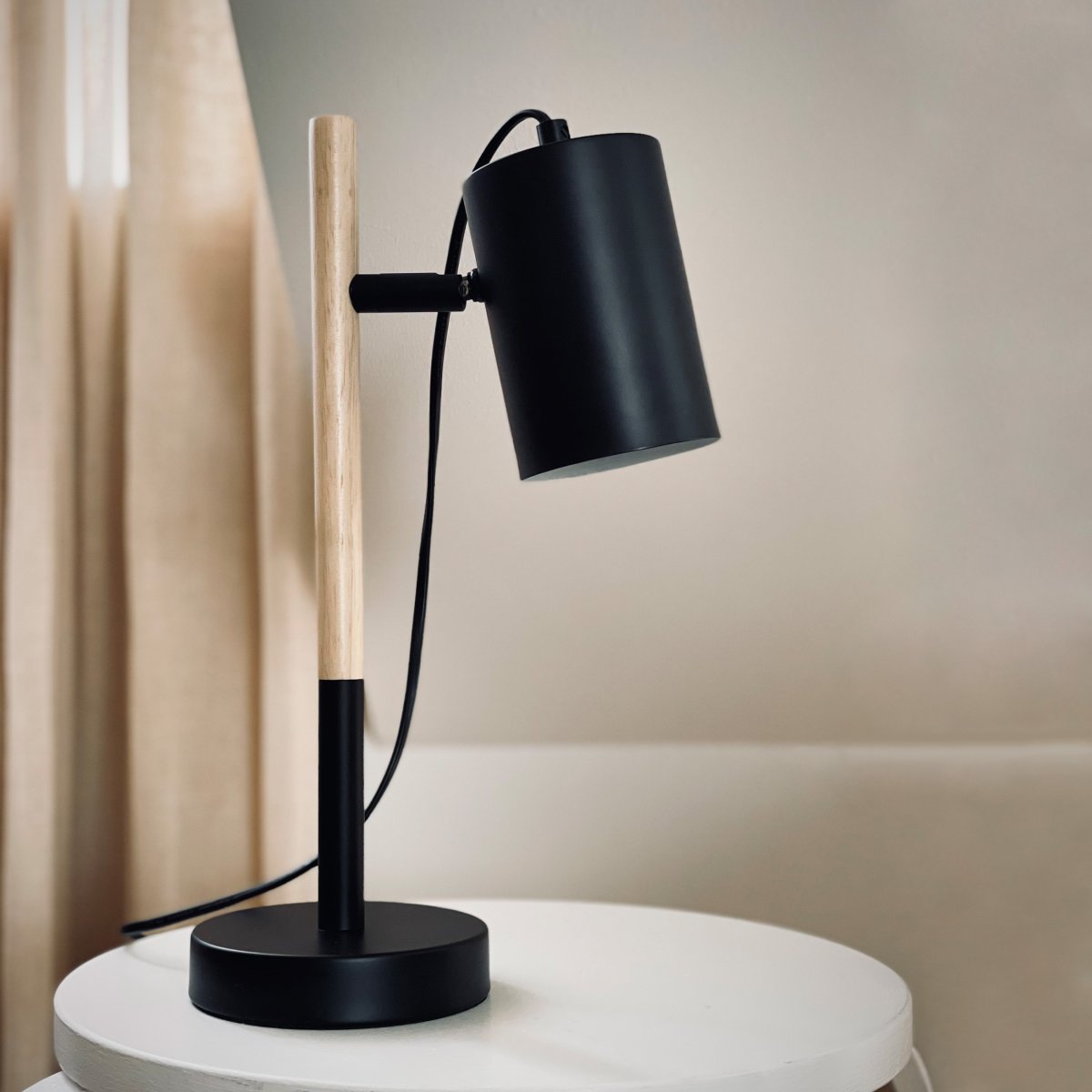 Woody 35cm Svart skrivbordslampa från Dyberg Larsen - Lampan har en svart metallsk&auml;rm och bas som ger ett stilrent uttryck, medan benet &auml;r gjort av tr&auml; f&ouml;r en varm och inbjudande k&auml;nsla.