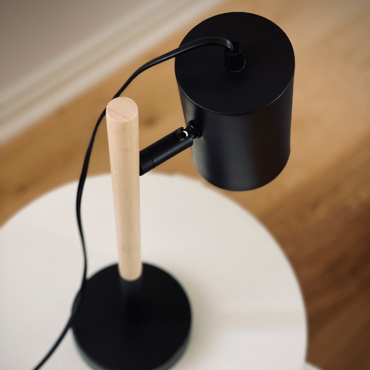 Woody 35cm Svart skrivbordslampa från Dyberg Larsen - Lampan har en svart metallsk&auml;rm och bas som ger ett stilrent uttryck, medan benet &auml;r gjort av tr&auml; f&ouml;r en varm och inbjudande k&auml;nsla.