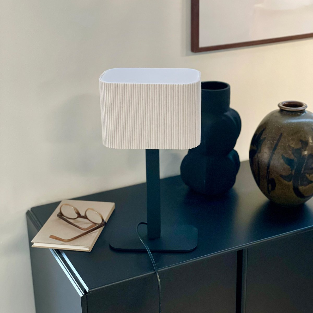 Calix oval 40cm Svart bordslampa från Dyberg Larsen - Den ribbade, naturf&auml;rgade sk&auml;rmen av textil medf&ouml;r en v&auml;rme till rummet och i kombination med den svarta metallfoten passar Calix in i alla stilar och hem.