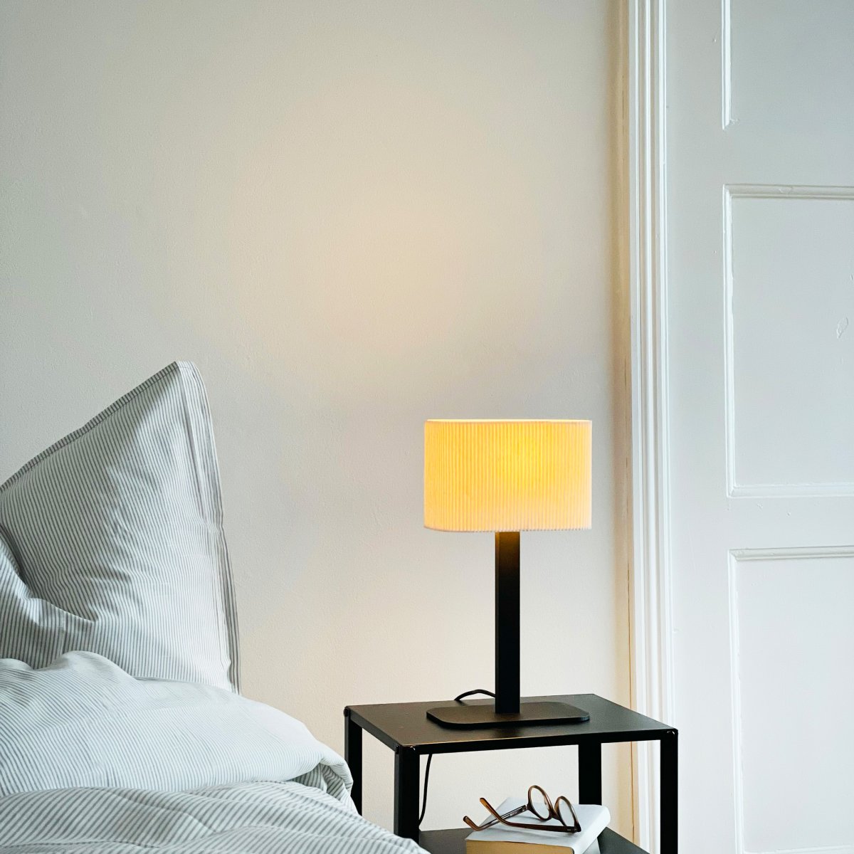 Calix oval 40cm Svart bordslampa från Dyberg Larsen - Den ribbade, naturf&auml;rgade sk&auml;rmen av textil medf&ouml;r en v&auml;rme till rummet och i kombination med den svarta metallfoten passar Calix in i alla stilar och hem.