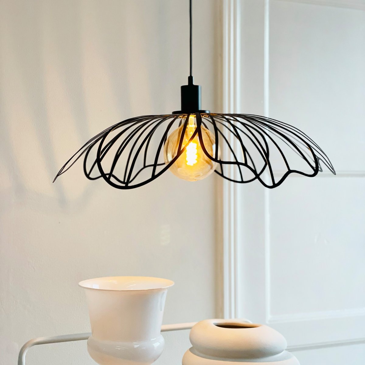 Blumen Ø60 Mattsvart taklampa från Dyberg Larsen - Den sprider ett sofistikerat ljus och fungerar som en unik mittpunkt i hemmet, vare sig den h&auml;nger &ouml;ver matbordet, i vardagsrummet eller i entr&eacute;n.