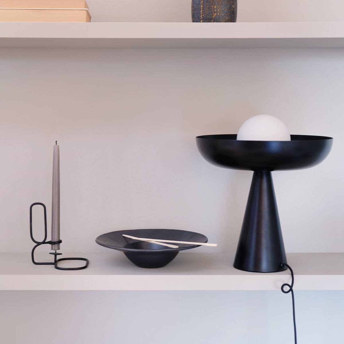 Ava 35cm Svart bordslampa från Dyberg Larsen - Kombinationen av den svarta metallbasen och den eleganta glaskupolen omger ljuset p&aring; ett f&ouml;rtrollande s&auml;tt, vilket skapar en unik och i&ouml;gonfallande ljuspunkt i din inredning.