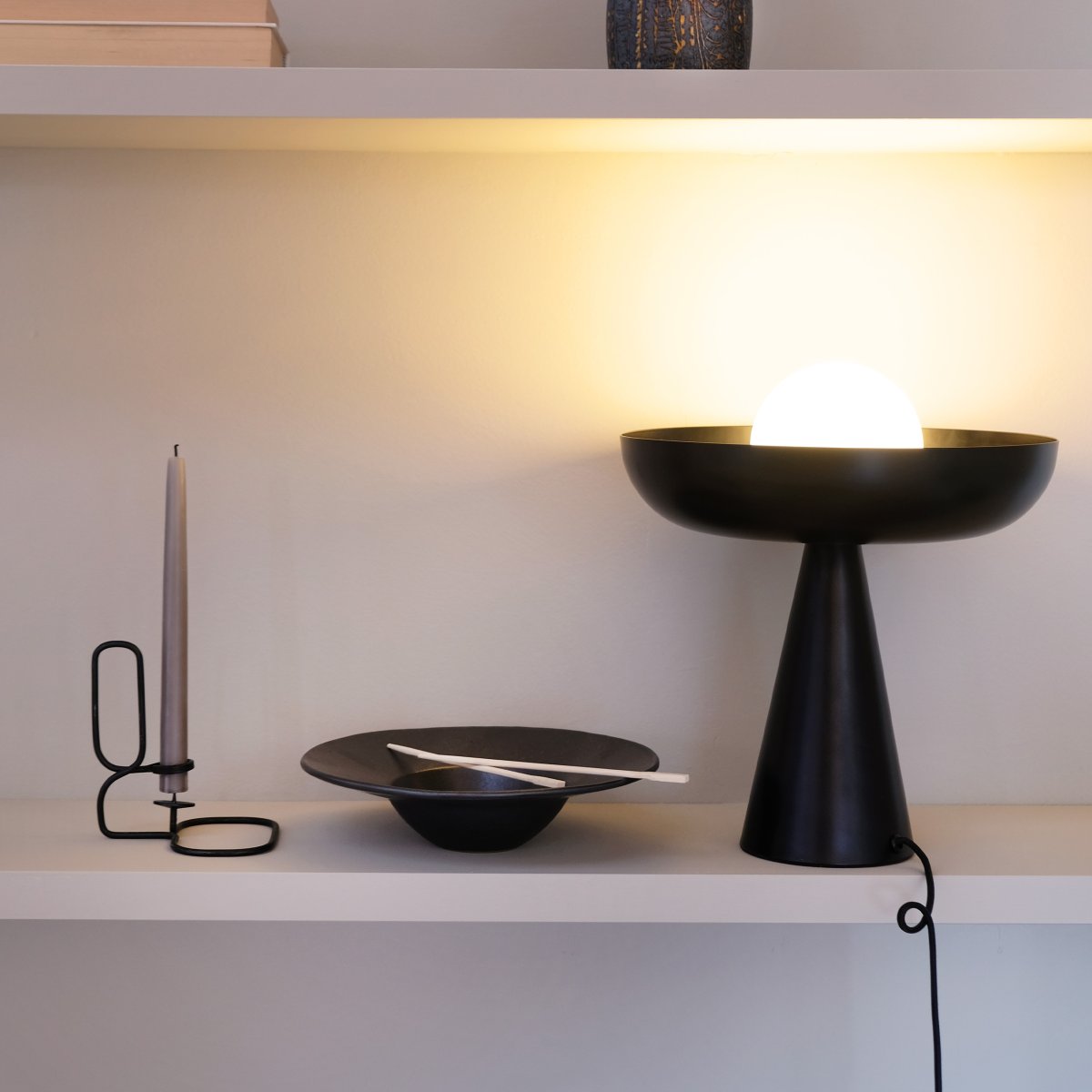 Ava 35cm Svart bordslampa från Dyberg Larsen - Kombinationen av den svarta metallbasen och den eleganta glaskupolen omger ljuset p&aring; ett f&ouml;rtrollande s&auml;tt, vilket skapar en unik och i&ouml;gonfallande ljuspunkt i din inredning.