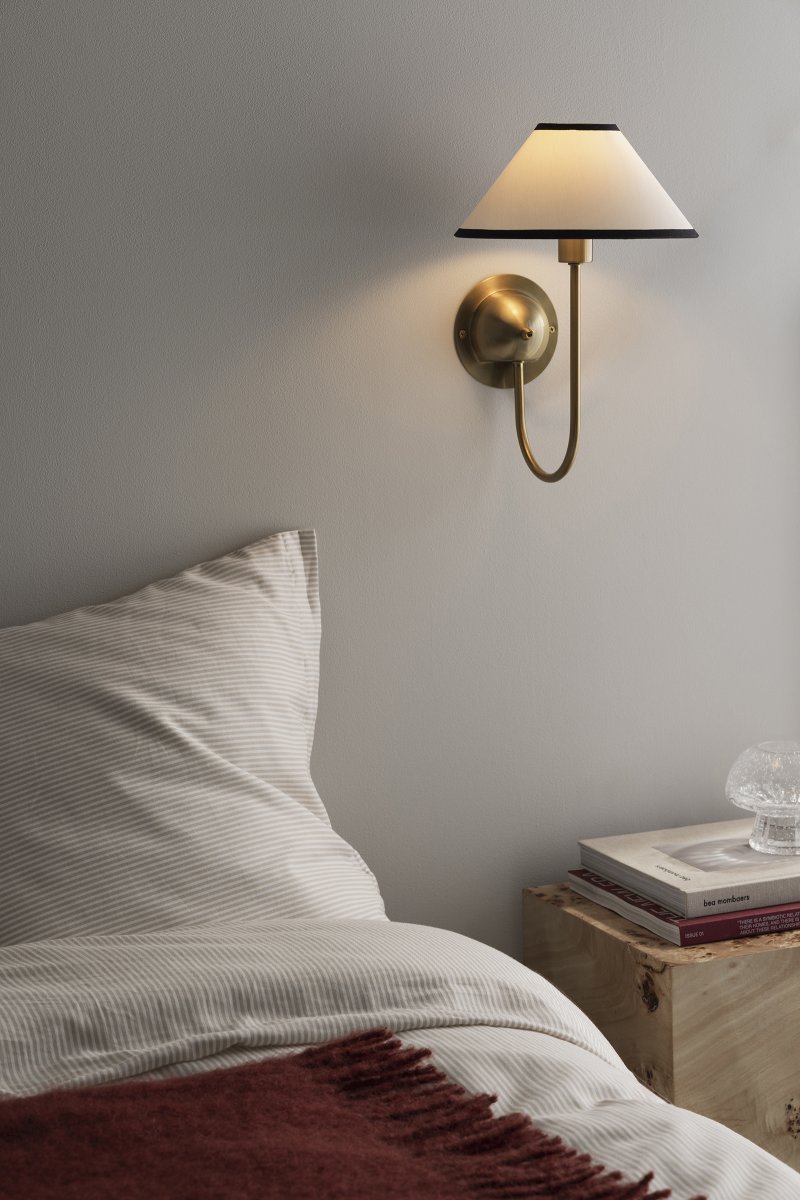 Iris 32cm Mässing/krämvit vägglampa från Globen Lighting - Den mjukt b&ouml;jda armen kombineras med en kr&auml;mvit textilsk&auml;rm som skapar ett varmt och klassiskt uttryck.