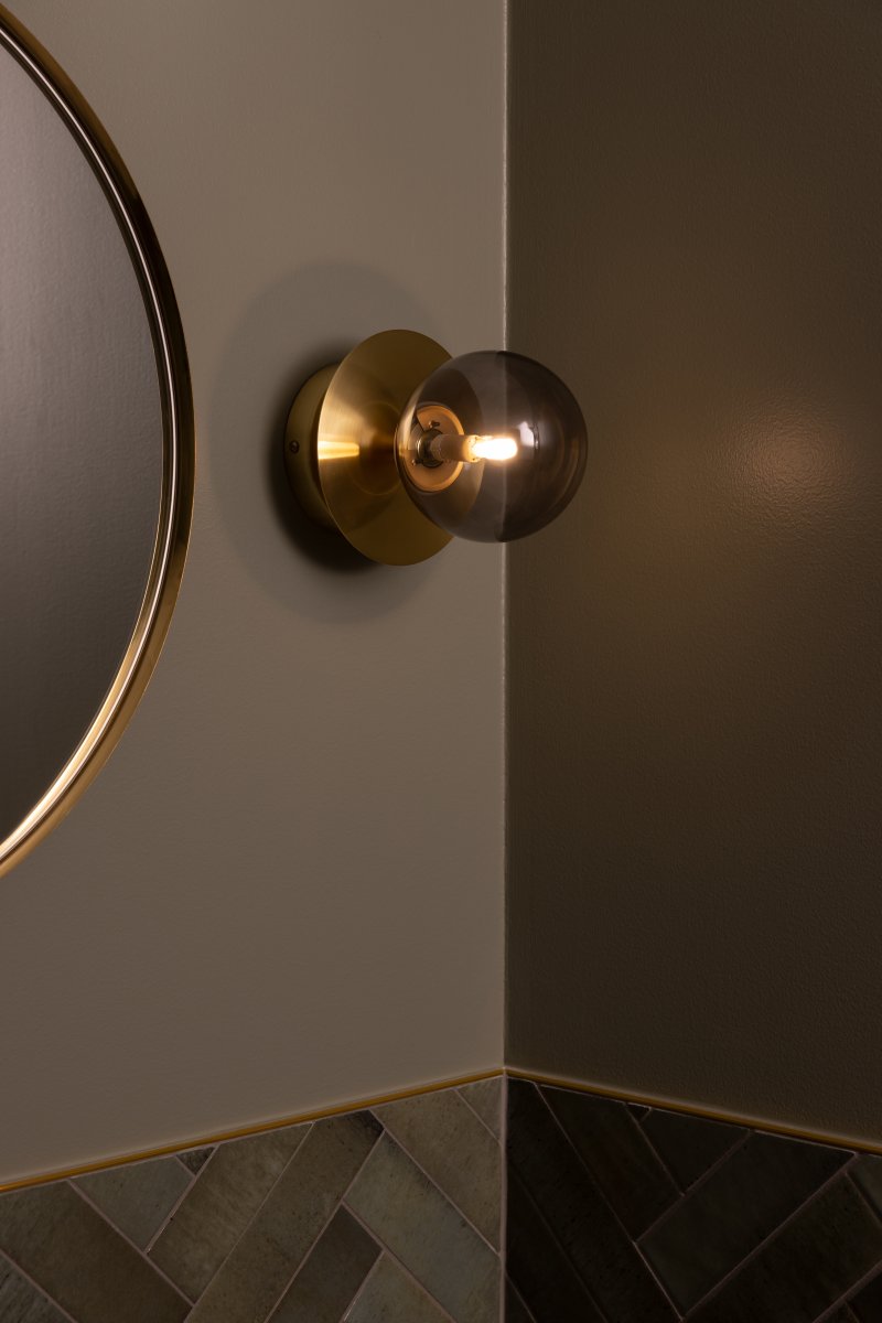 Art Deco Ø16 Borstad mässing/rökfärgad badrumslampa från Globen Lighting - Lampan &auml;r tillverkad av metall och har en r&ouml;kf&auml;rgad glaskupa som skapar en fin ljusspridning i rummet.