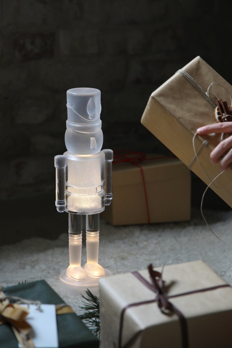 Douglas Transparent från Markslöjd - Formen av en n&ouml;tkn&auml;ppare med varmvitt ljus och dekorativt glitter.