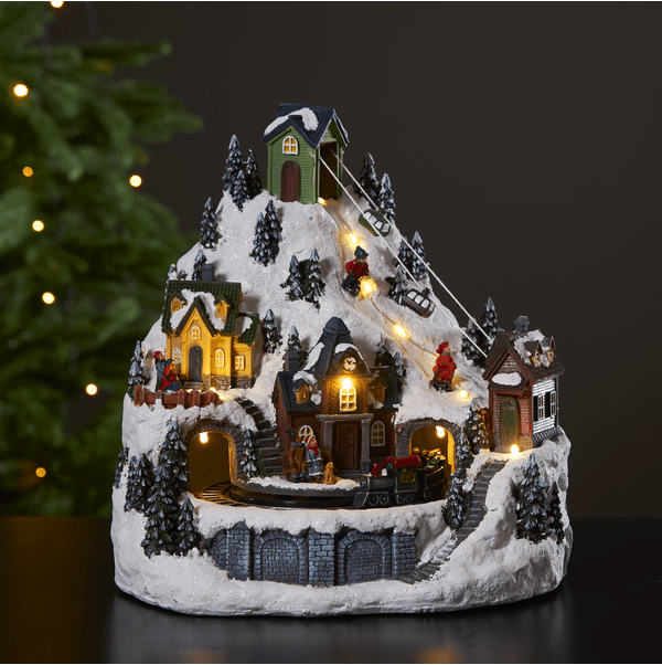 Alpville 25cm Flerfärgad från Star Trading - Vacker juldekoration i form av ett dekorativt vinterlandskap med linbana, skid&aring;kare och t&aring;gstation med roterande t&aring;g.