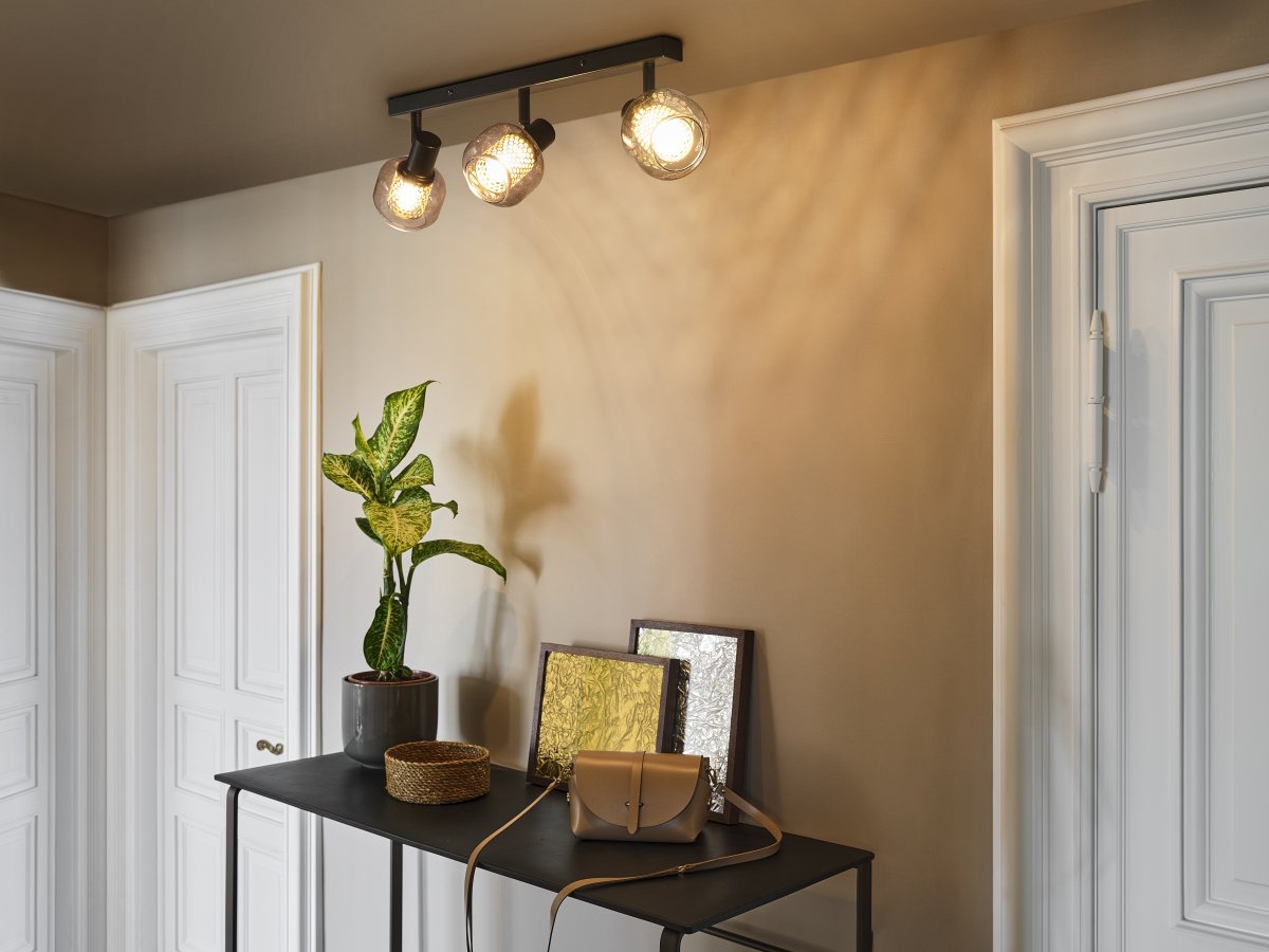 Firefly 3 Svart spotlight från Osram - De r&ouml;rliga spotlightsen med sk&auml;rmar av gr&aring;tonat glas i kombination med de guldiga detaljh&ouml;ljet som omfamnar ljusk&auml;llorna bidrar med en elegans till rummet.