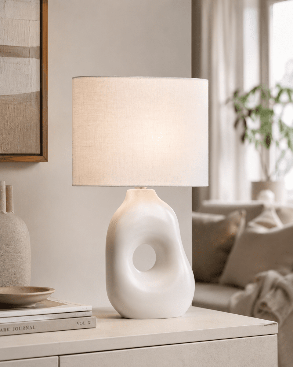 Pikazo 45cm Vit bordslampa från Lampan - Pikazo bordslampa har en unik keramisk fot med skulptural form och ett dekorativt genomg&aring;ende h&aring;l, kombinerad med en vit och oval linnesk&auml;rm.