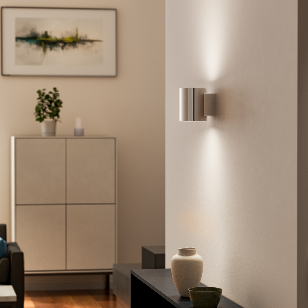 Evoke S Krom vägglampa från Herstal - Den smarta konstruktionen med b&aring;de upp- och nerljus g&ouml;r den till ett utm&auml;rkt val f&ouml;r att belysa din hall, vardagsrum eller sovrum p&aring; ett subtilt men effektfullt s&auml;tt.