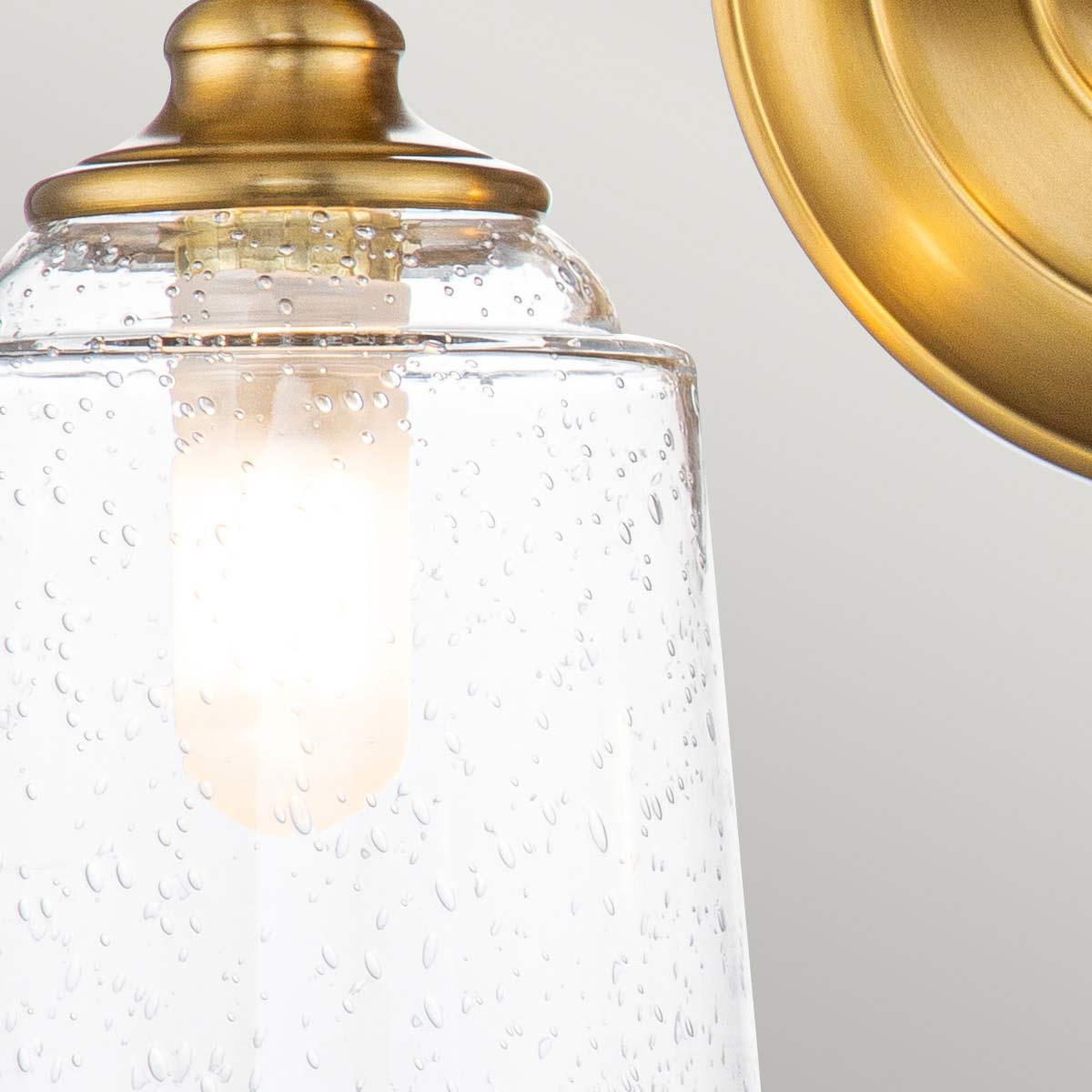 Huguenot Lake 33cm Mässing badrumslampa från Elstead Lighting - Den eleganta cirkul&auml;ra detaljen och handslipade f&auml;sten ger en k&auml;nsla av traditionell hantverkskonst, medan de klara, strukturerade glasen skapar ett mjukt och inbjudande ljus.