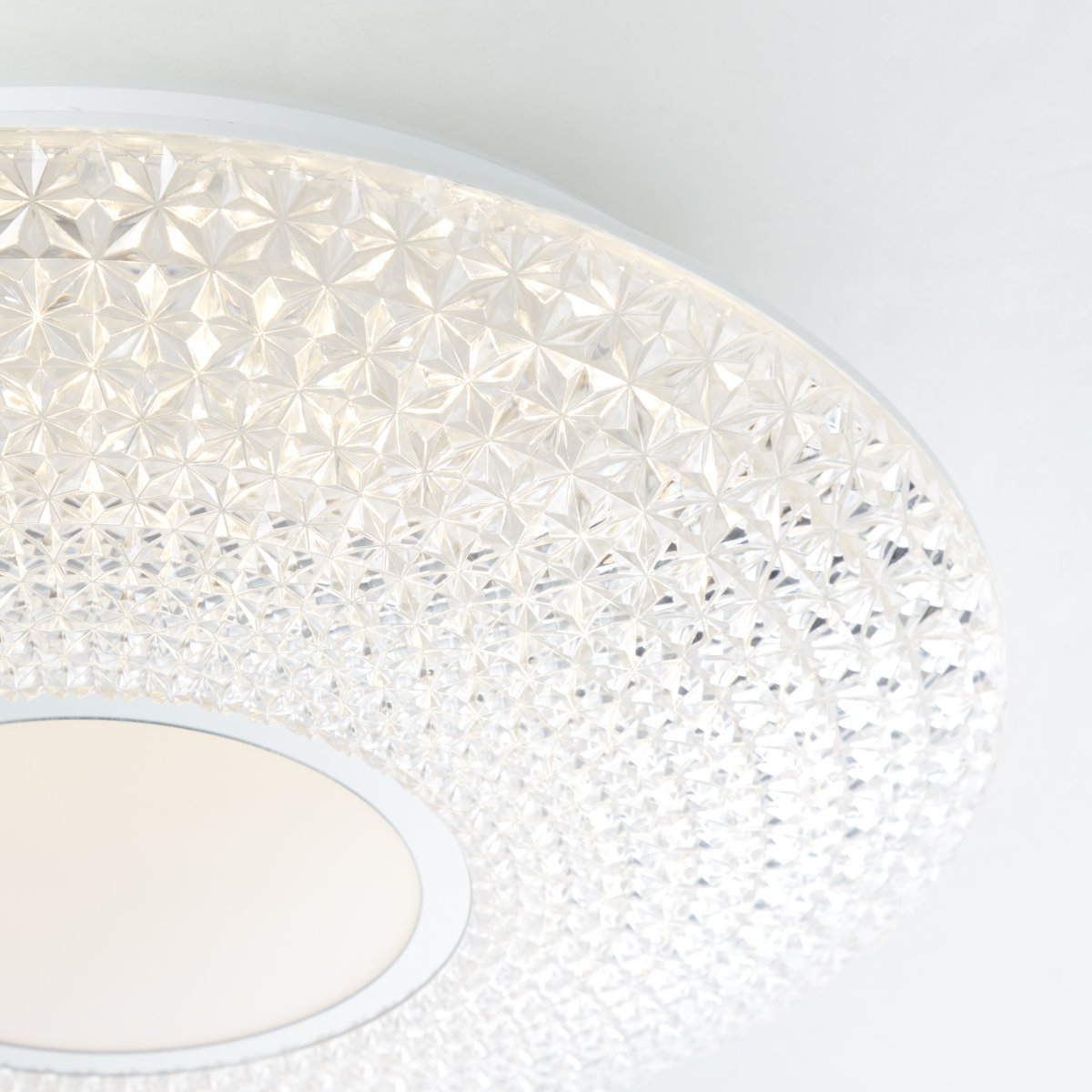Lucian Ø40 Vit plafond från Brilliant - LED panelen omfamnas av den klara sk&auml;rmen med sm&aring; utformade prismor vilket skapar en vacker ljusbild i rummet n&auml;r lampan &auml;r t&auml;nd.