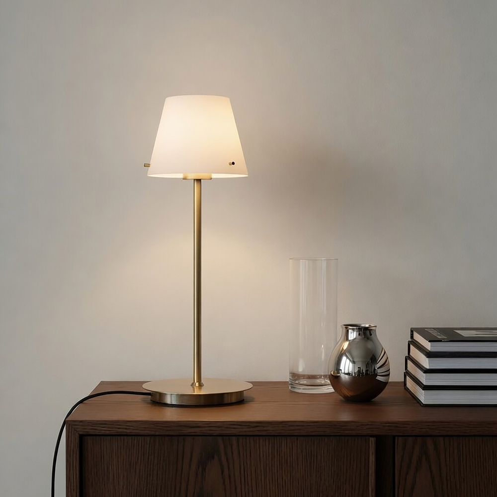 Gil 34cm Satin mässing bordslampa från Herstal - Den &auml;r tillverkad av metall med satin m&auml;ssingfinish och har en sk&auml;rm i vitt glas som sprider ett mjukt och behagligt ljus.