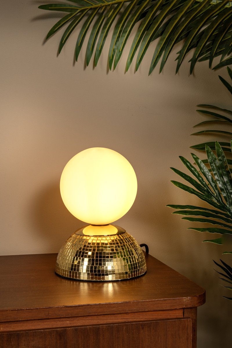 Glitzer 18cm Guld barnlampa från Lucide - Lampfoten i metall har en glittrande, spegelliknande yta som ger ett effektfullt intryck, medan den runda glaskupan sprider ett mjukt och behagligt ljus.
