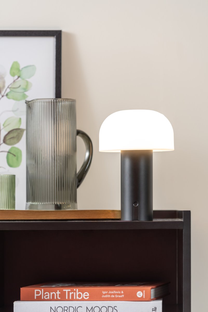 Luca LED 22cm Svart portabel från Leitmotiv - Den &auml;r tillverkad i metall med en mattsvart finish och har en mj&ouml;lkvit plastkupa som sprider ett mjukt och behagligt ljus.